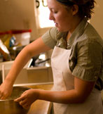 A baker in an apron mixing dough by hand in the cafe kitchen