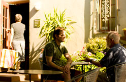 People at patio tables among potted plants in the evening light